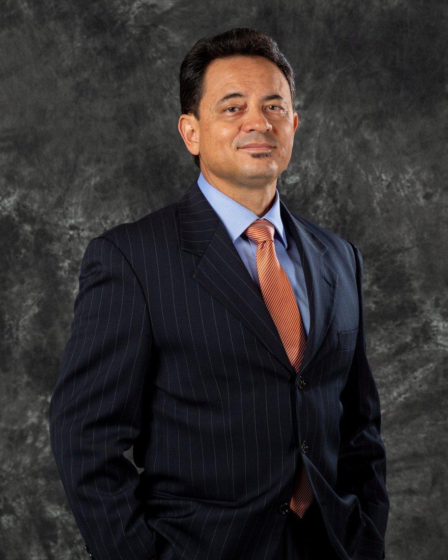 Francisco in a navy pinstripe suit, photographed against a mottled grey backdrop