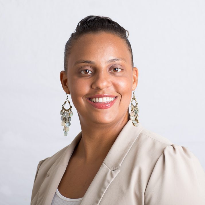 On-location headshot of a woman in a light cardigan against a mottled grey backdrop