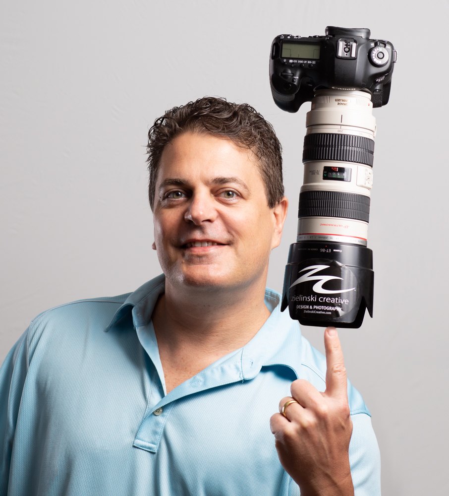 Jim Zielinski balancing a professional camera and telephoto lens on one finger